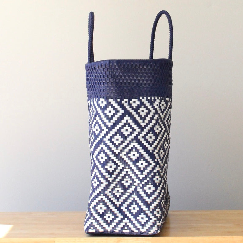 Woven basket with navy top and white geometric pattern on a wooden surface