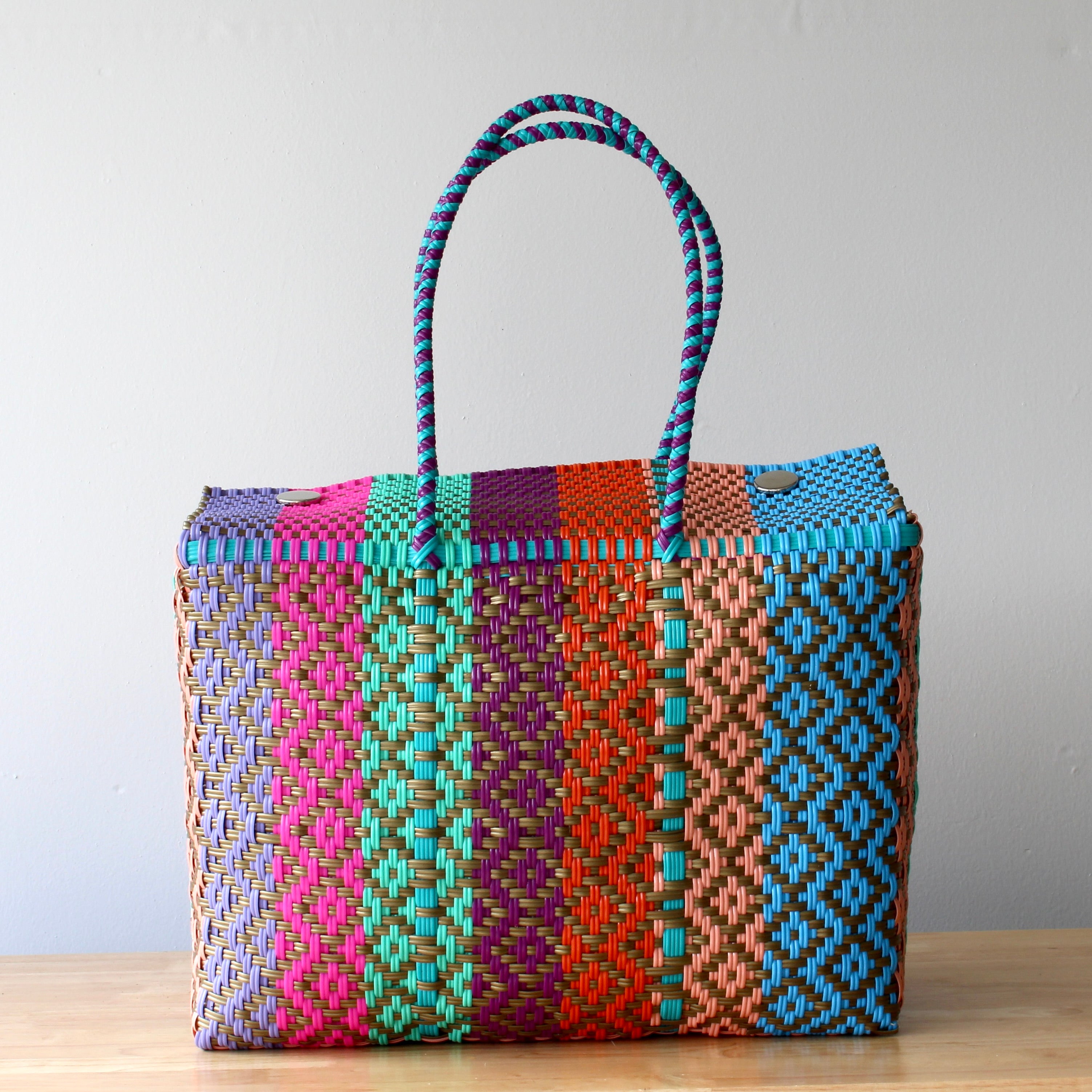 Colorful woven bag with pattern on a wooden surface and light gray background