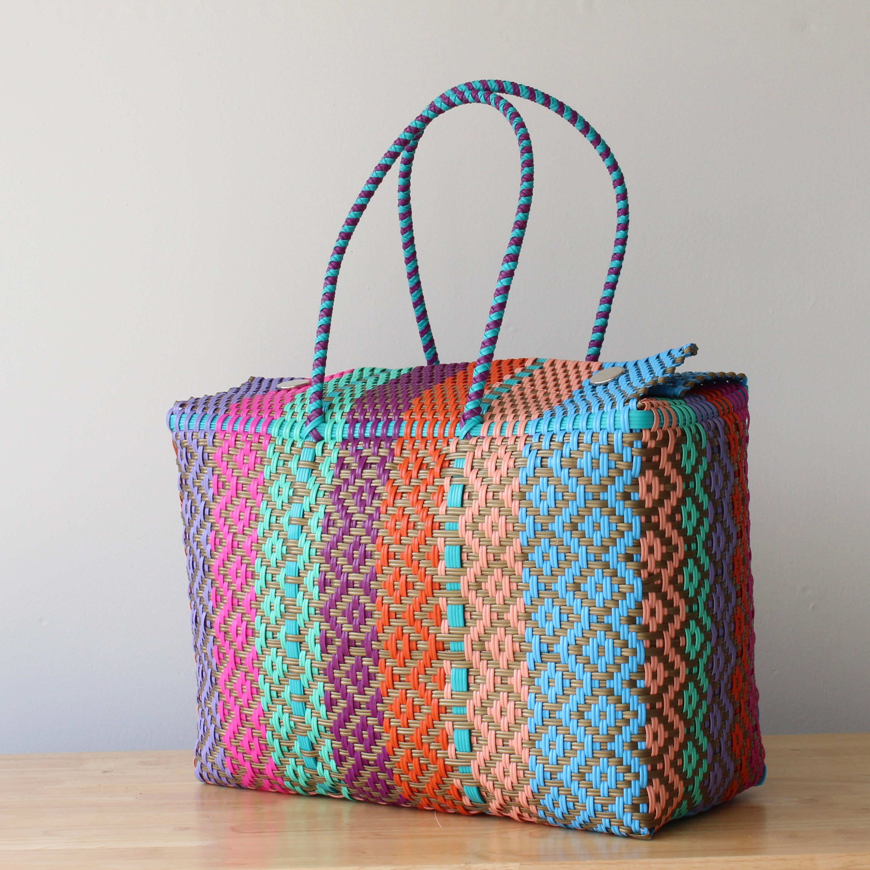 Colorful woven basket with pattern on a wooden surface and light gray background