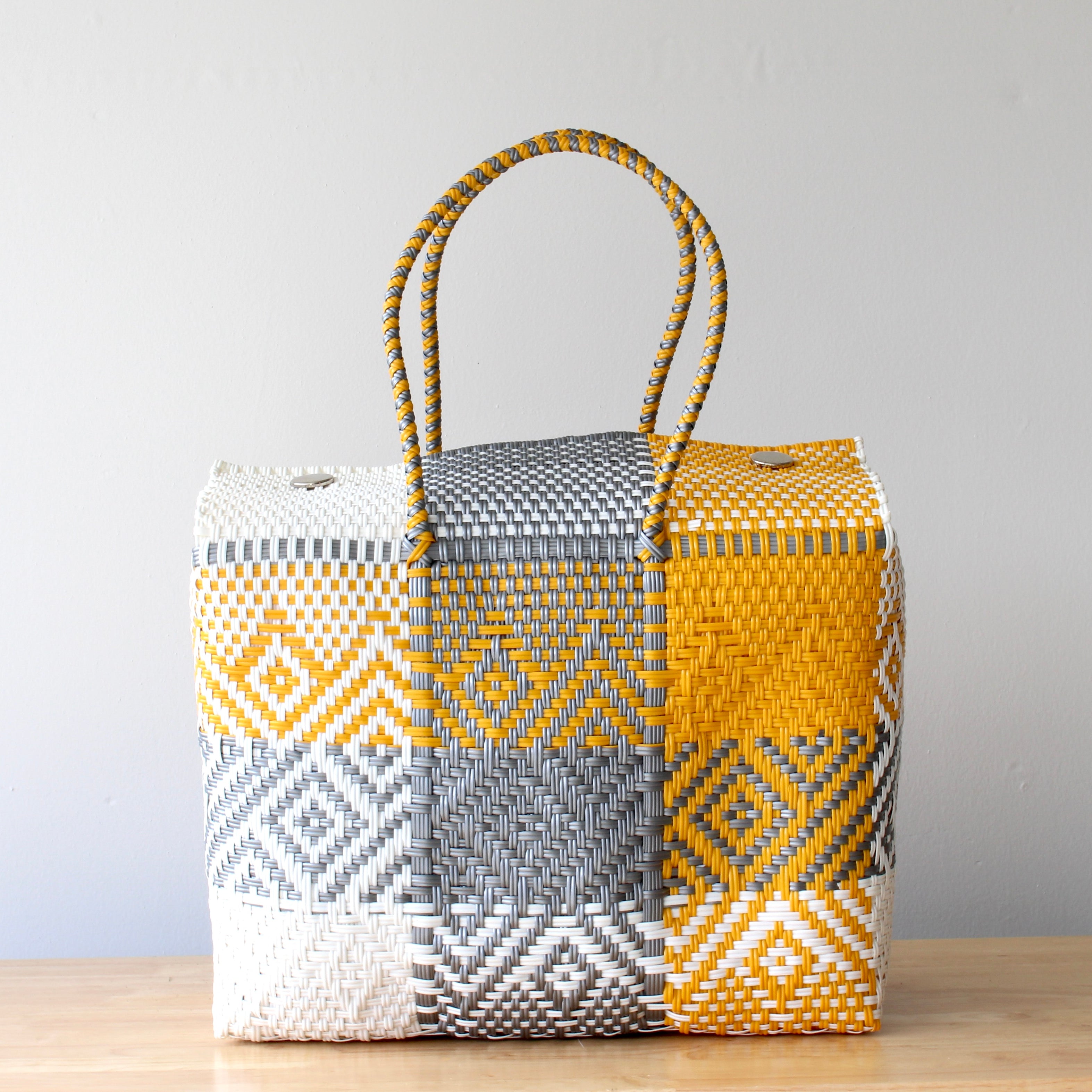 Woven basket with geometric pattern on a wooden surface and light gray background