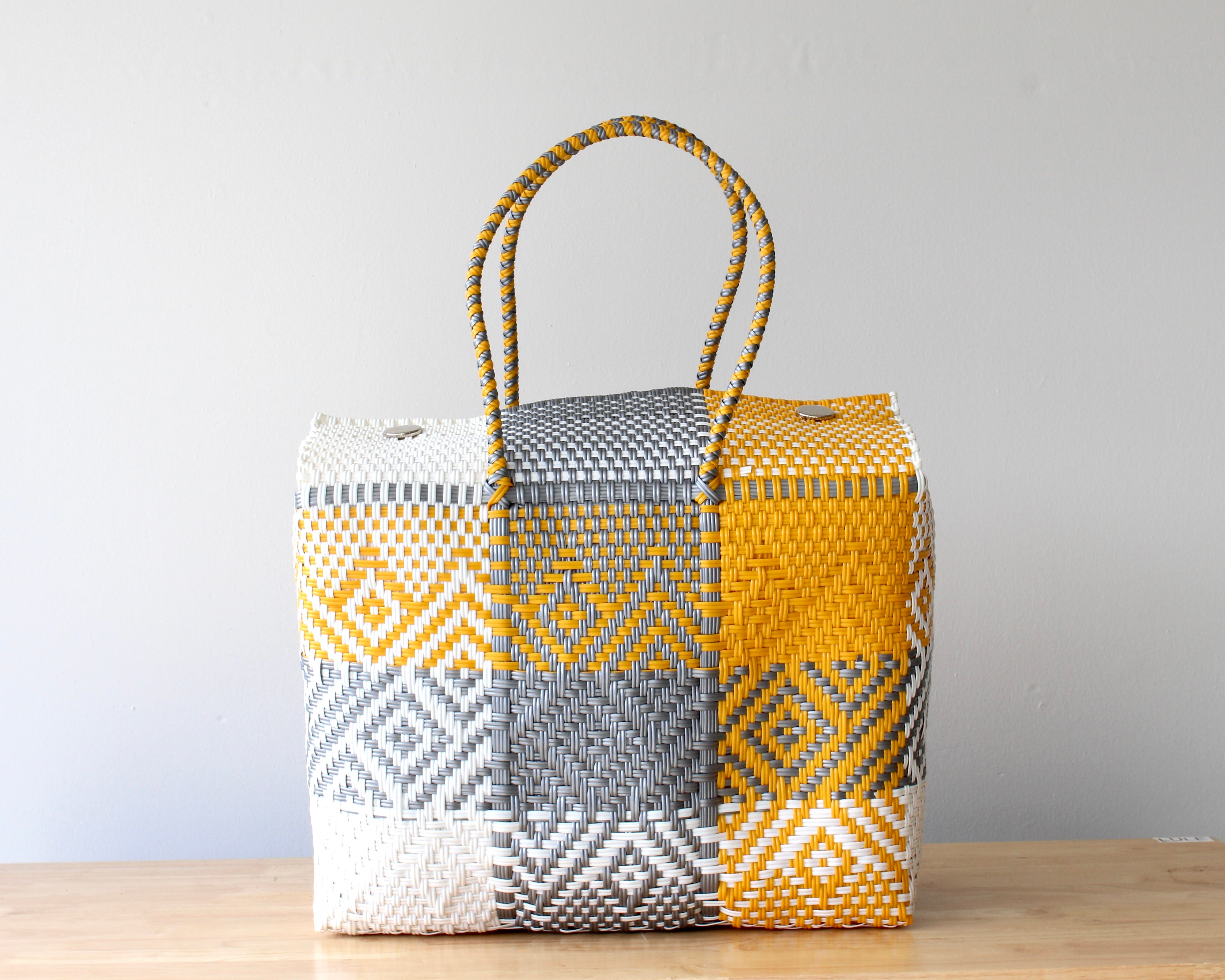 Woven basket with geometric pattern on a wooden surface and light gray background