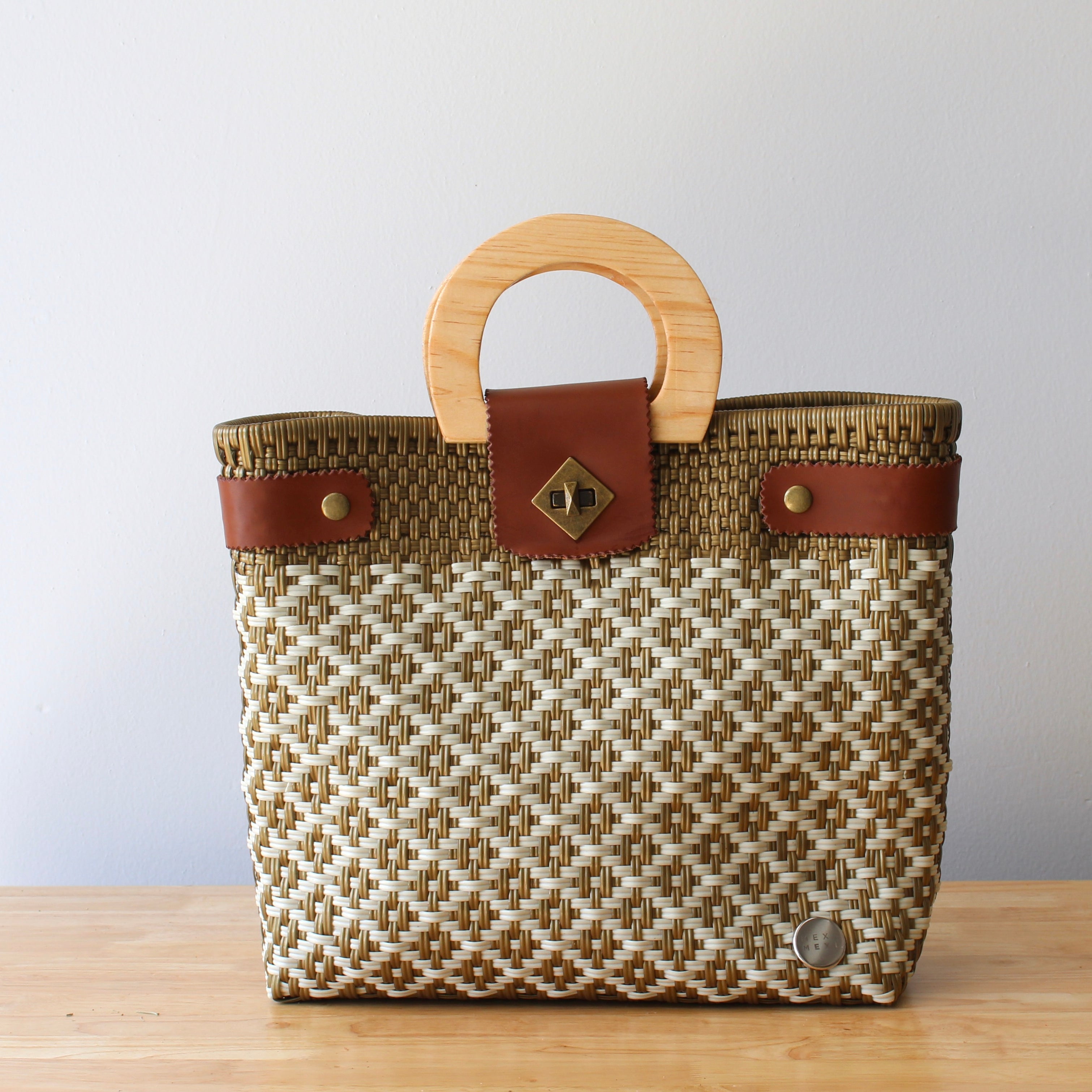 Beige and brown handwoven tote bag with leather handles on table