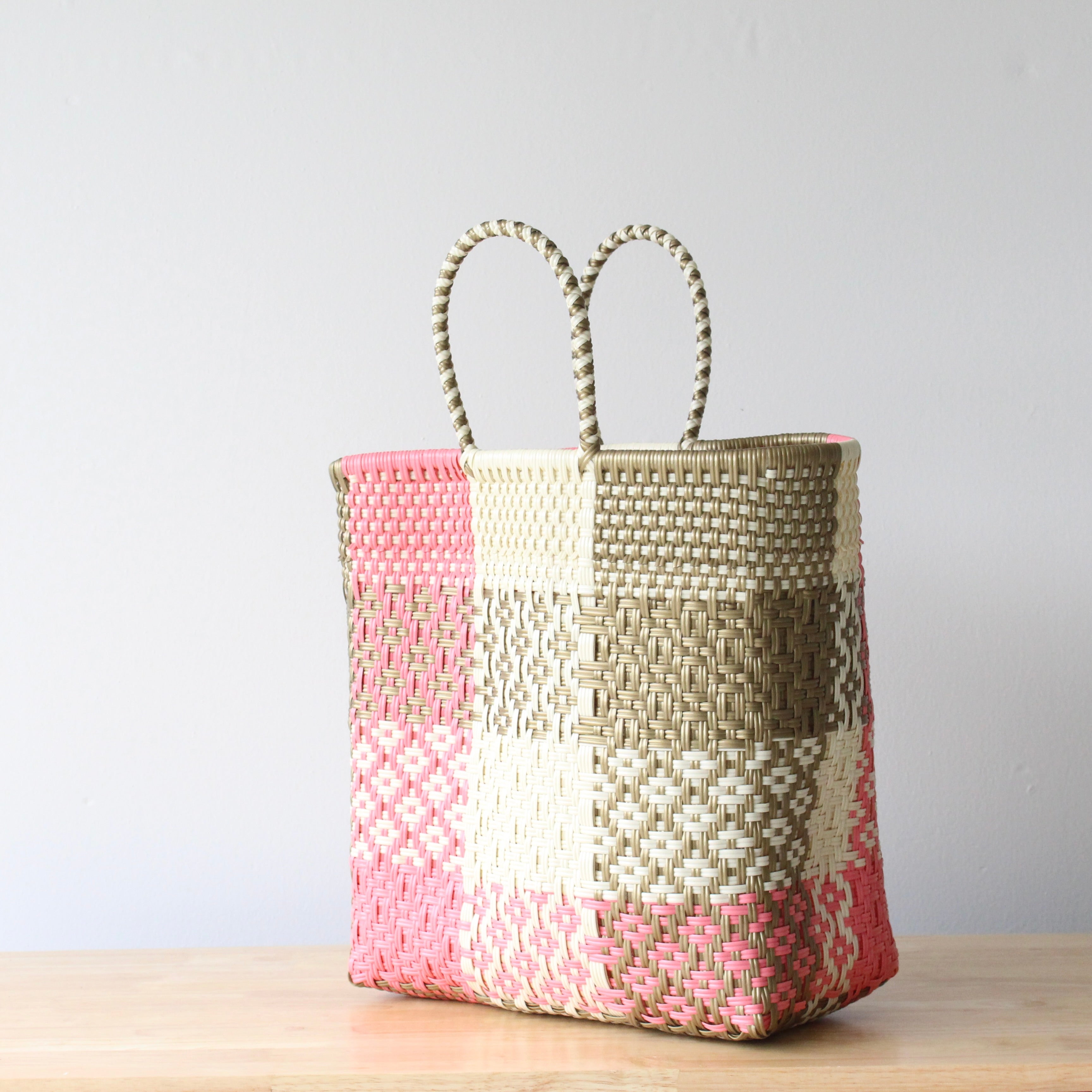 Side view of handmade Mexican plastic tote bag with pink and beige woven pattern