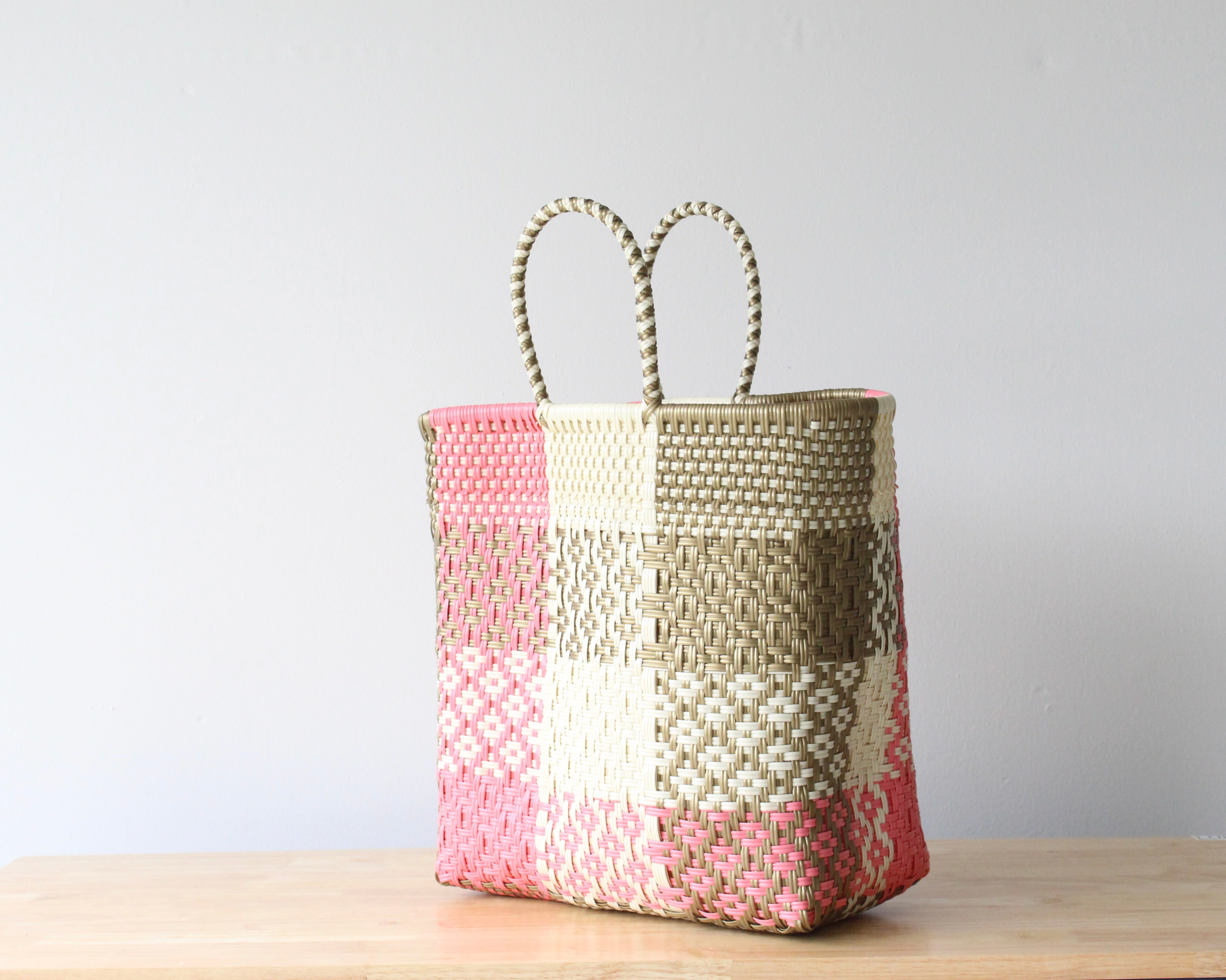 Side view of handmade Mexican plastic tote bag with pink and beige woven pattern