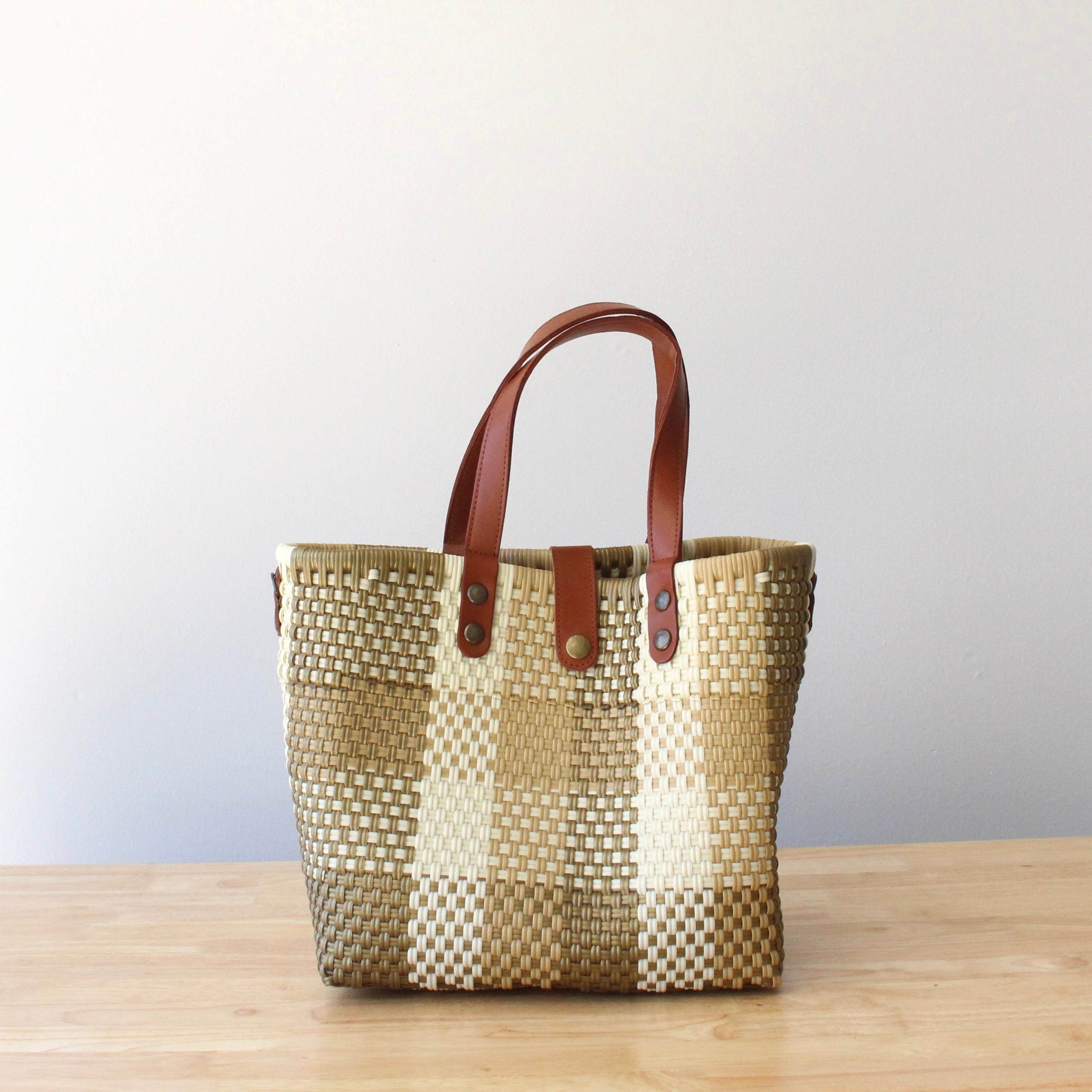 Handmade recycled plastic purse with brown leather handles, crafted by artisans in Mexico
