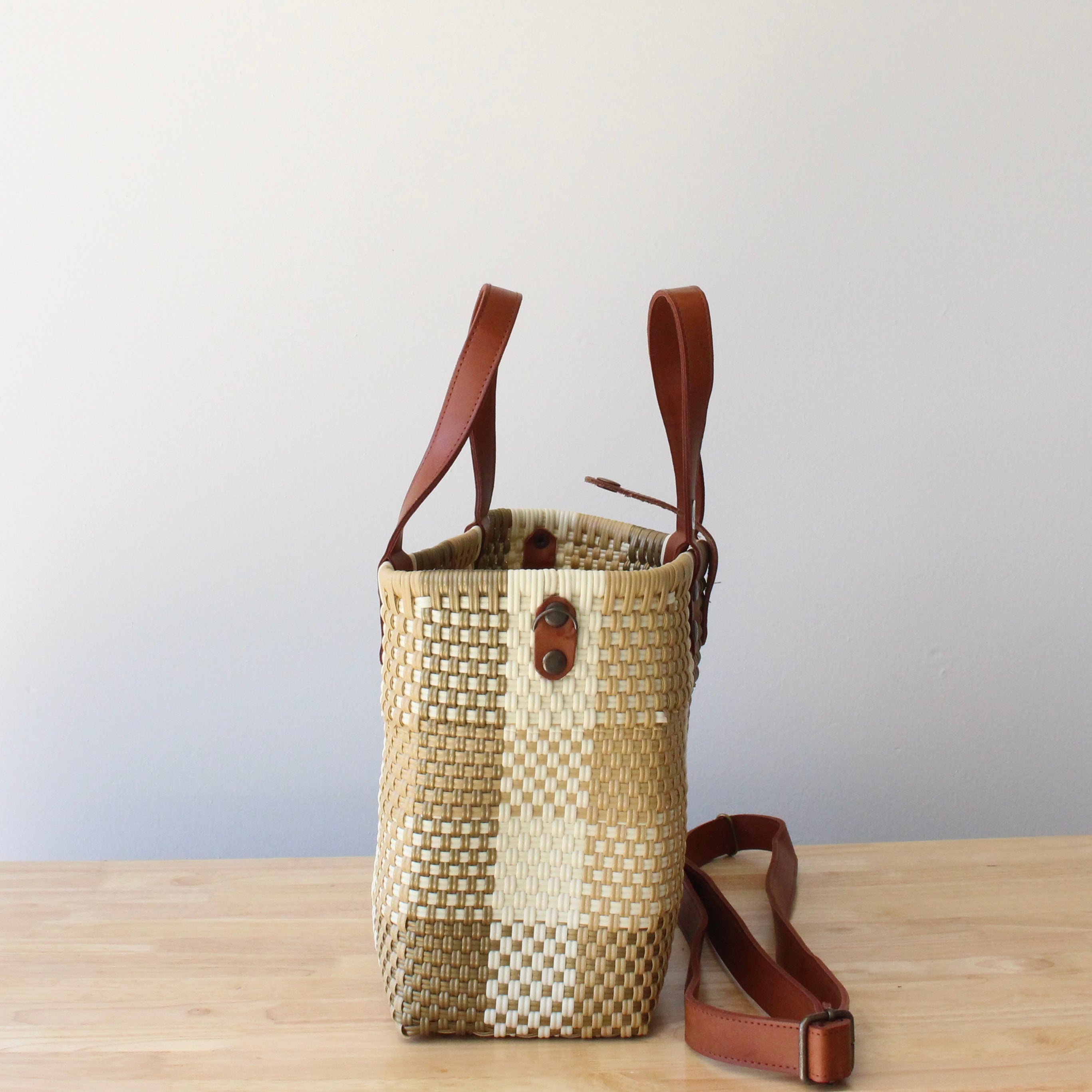 Close-up of the brown leather handles on a handmade recycled plastic purse, showcasing artisanal craftsmanship.