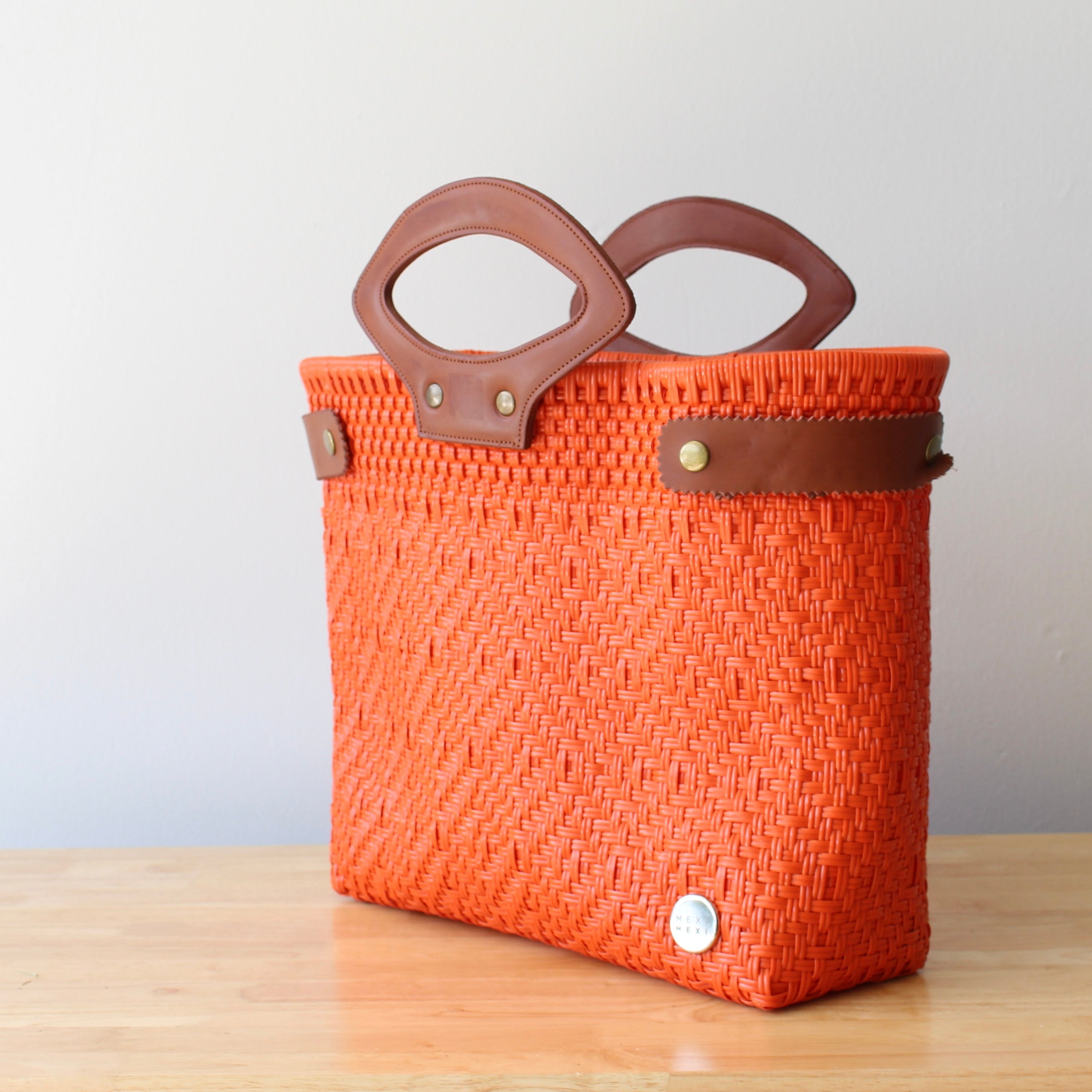 Eco-friendly orange woven purse on wooden table