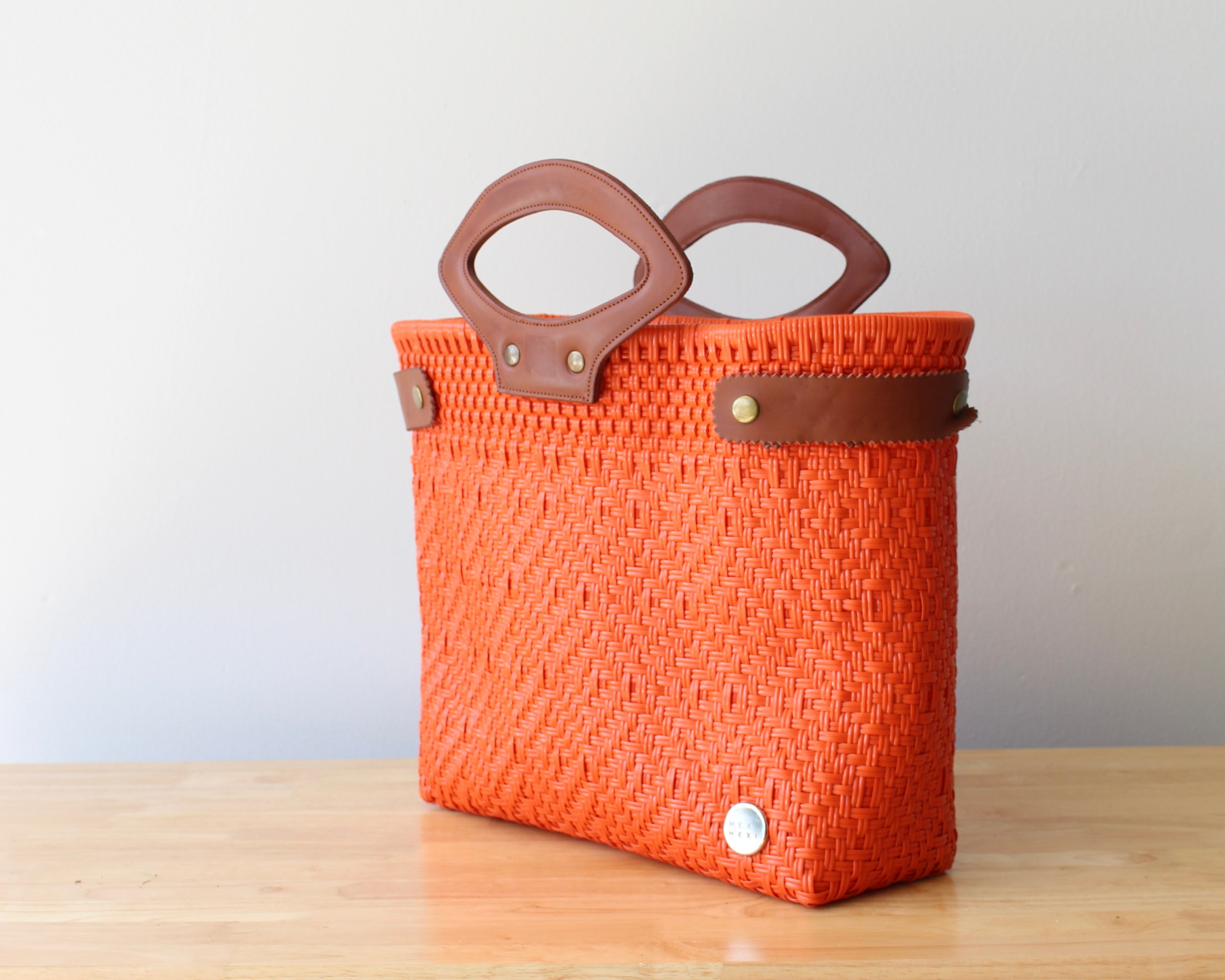 Eco-friendly orange woven purse on wooden table