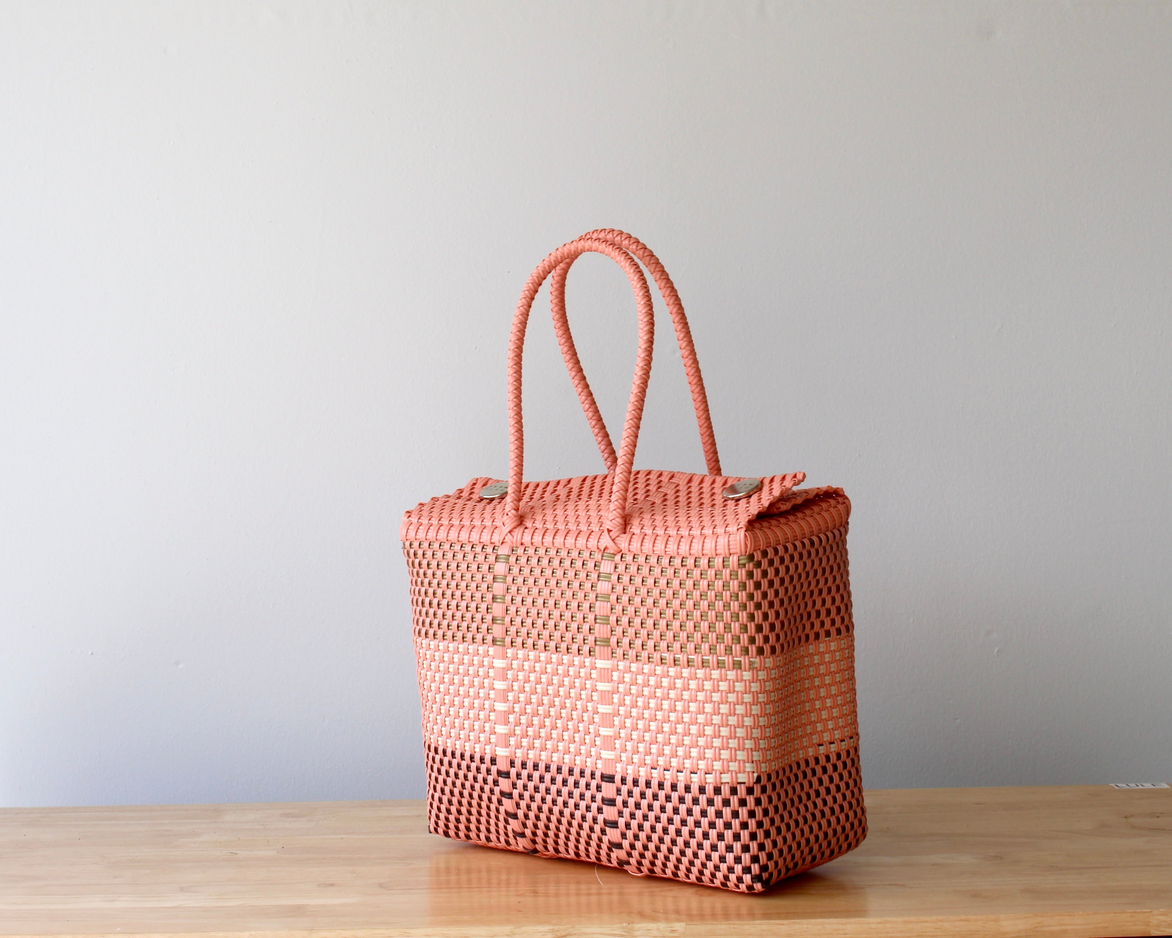 Woven pink bag on a wooden surface with a light gray background
