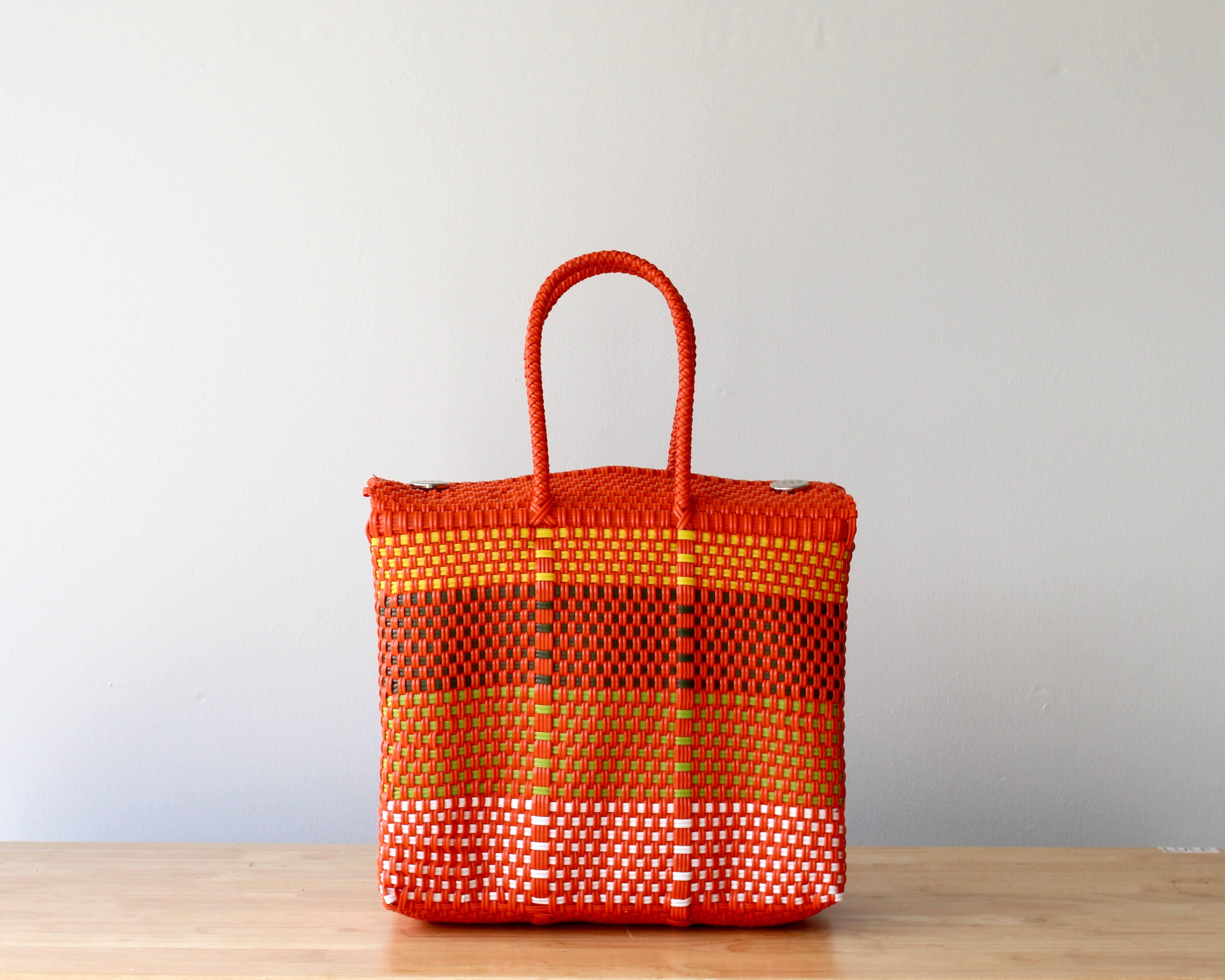 Orange woven basket on a wooden surface with a light gray background