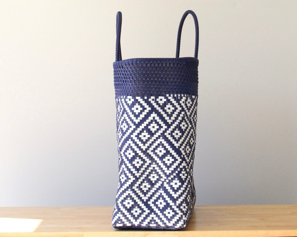 Woven basket with navy top and white geometric pattern on a wooden surface