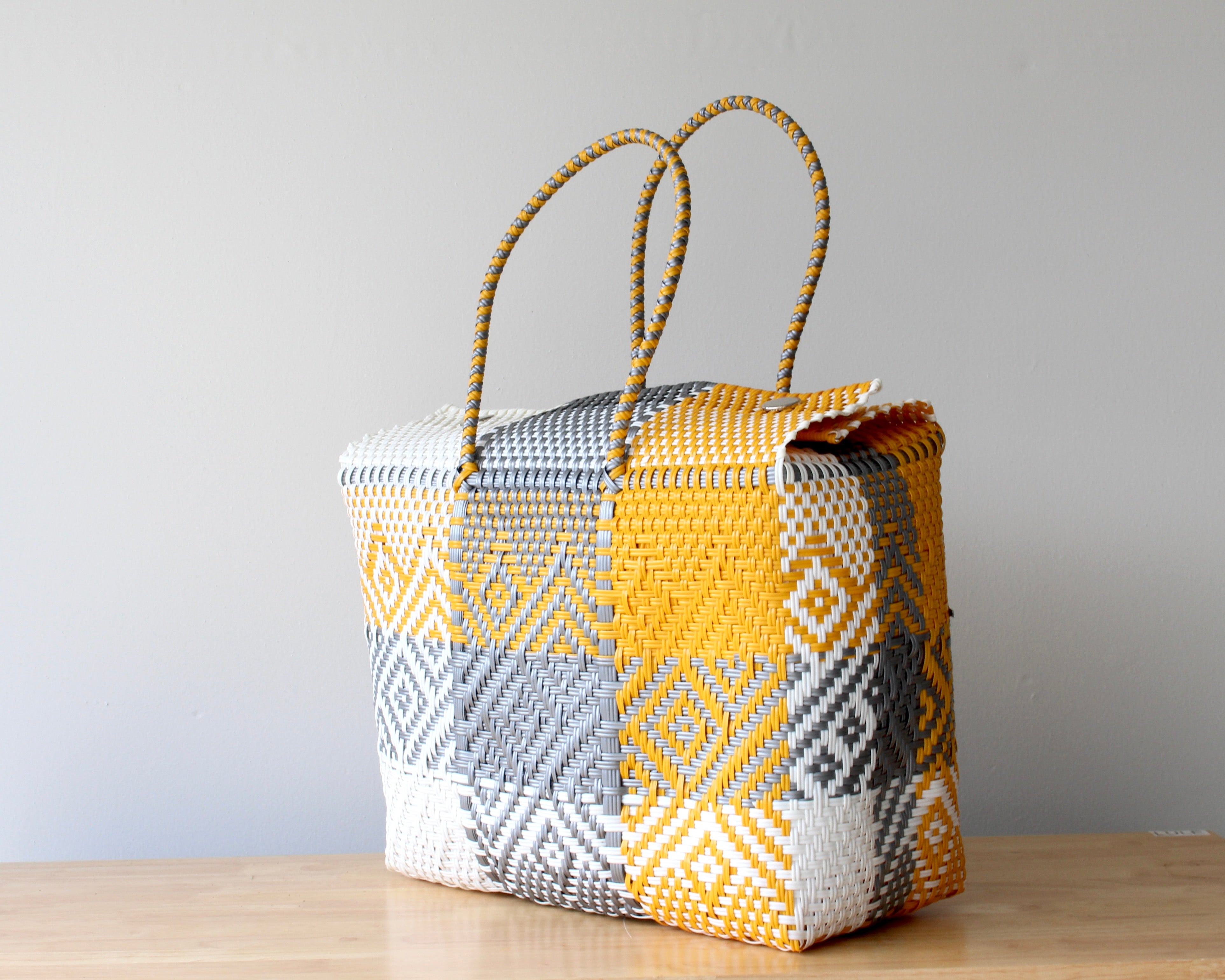 Woven basket with geometric pattern on a wooden surface and gray background