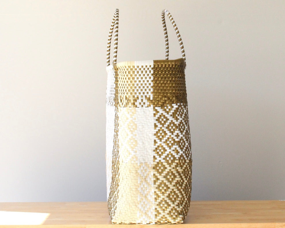 Woven basket with geometric pattern on a wooden surface and light gray background