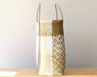 Woven basket with geometric pattern on a wooden surface and light gray background
