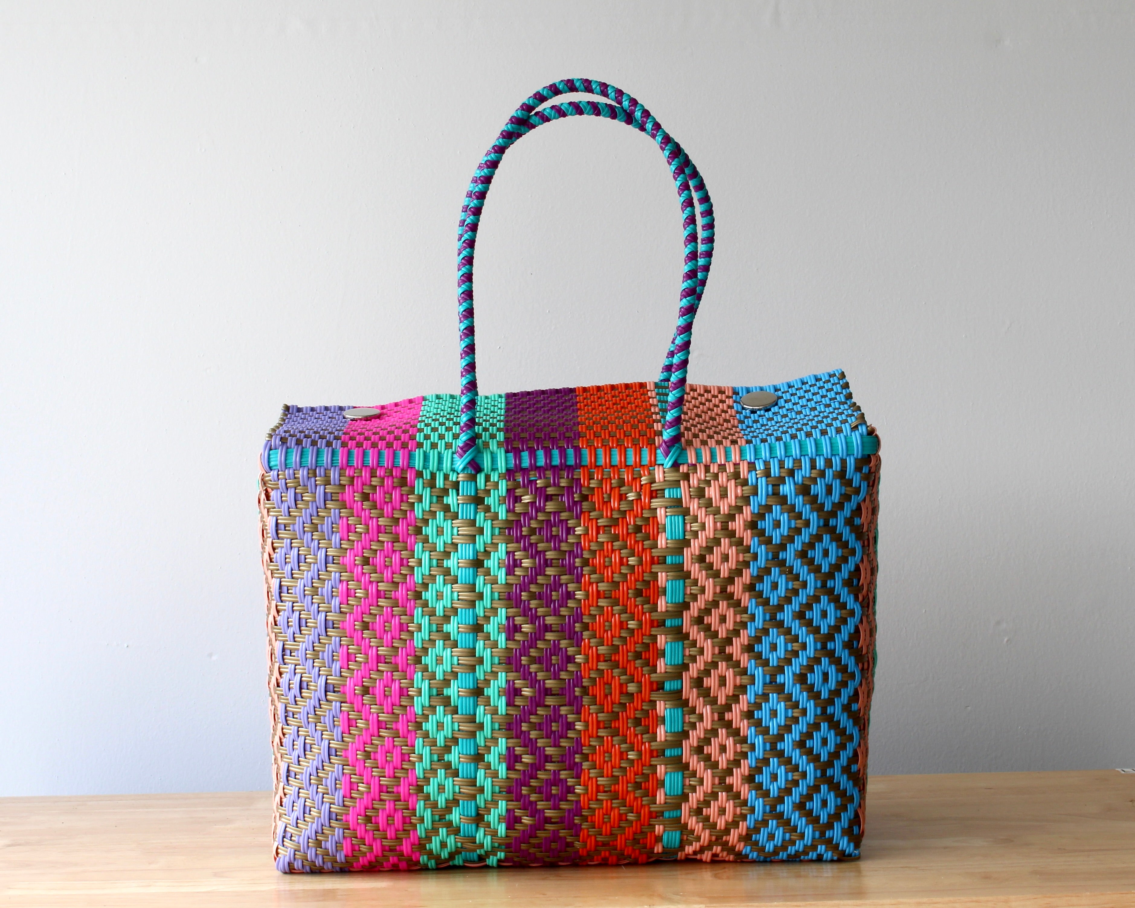 Colorful woven bag with pattern on a wooden surface and light gray background