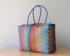 Colorful woven basket with pattern on a wooden surface and light gray background