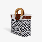 Black and white diamond handwoven basket bag with wood handles and brass-tone twist lock, angled view