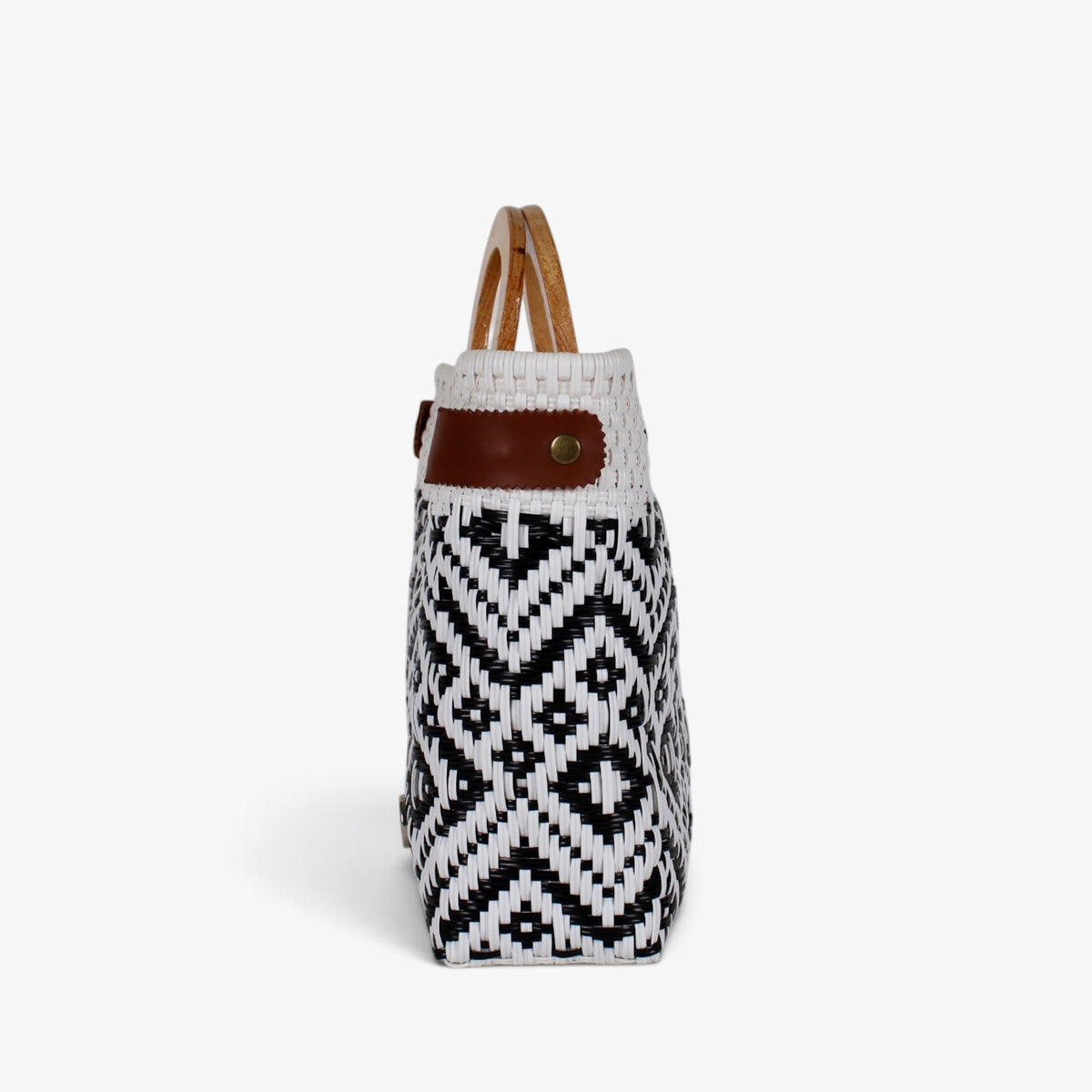 Side view of the black and white diamond basket bag showing its adjustable leather side strap