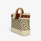 Cream and gold handwoven basket bag with wood handles and brass-tone twist lock, angled view