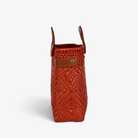 Side view of the terracotta woven tote showing its adjustable leather side strap