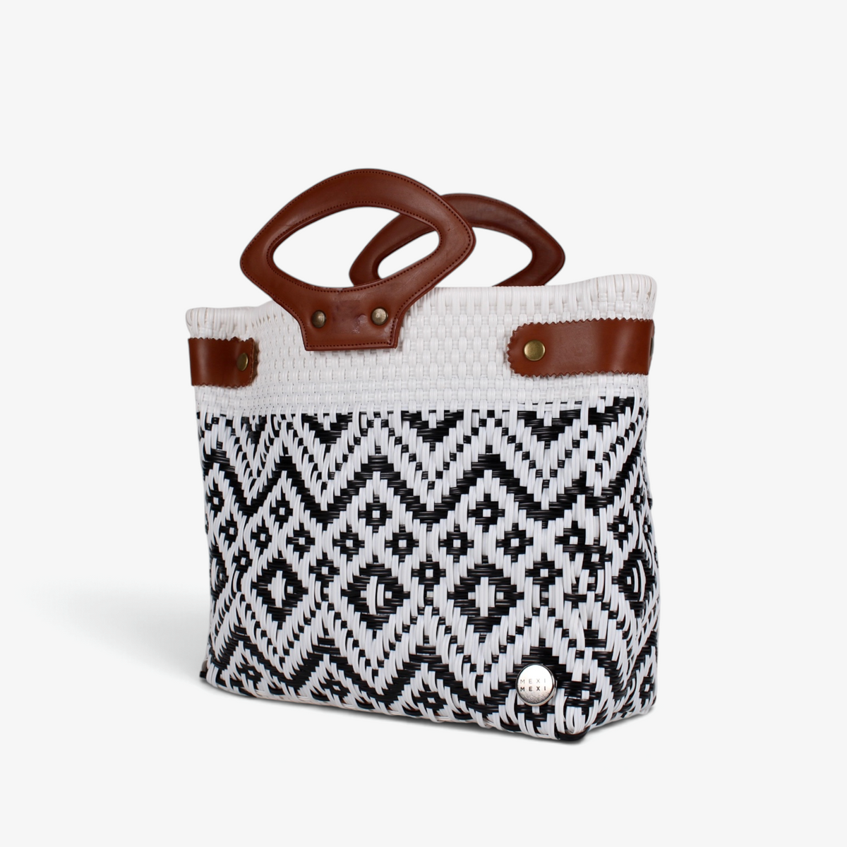 White and black patterned woven basket bag with brown genuine leather handles, angled view