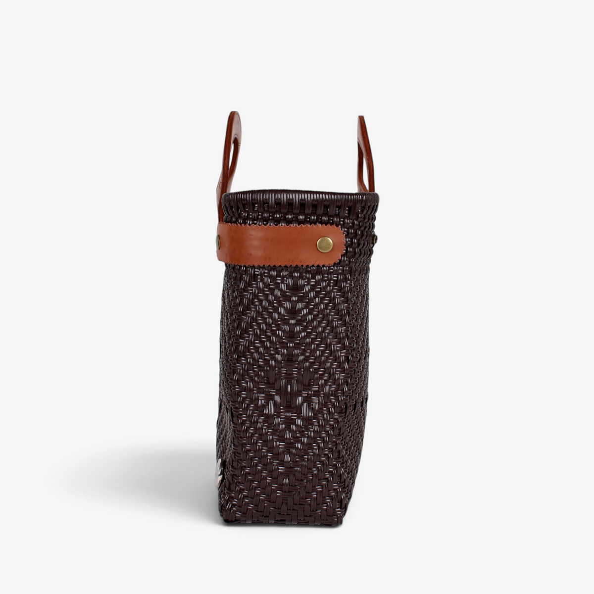 Side view of the chocolate brown woven tote showing its adjustable leather side strap