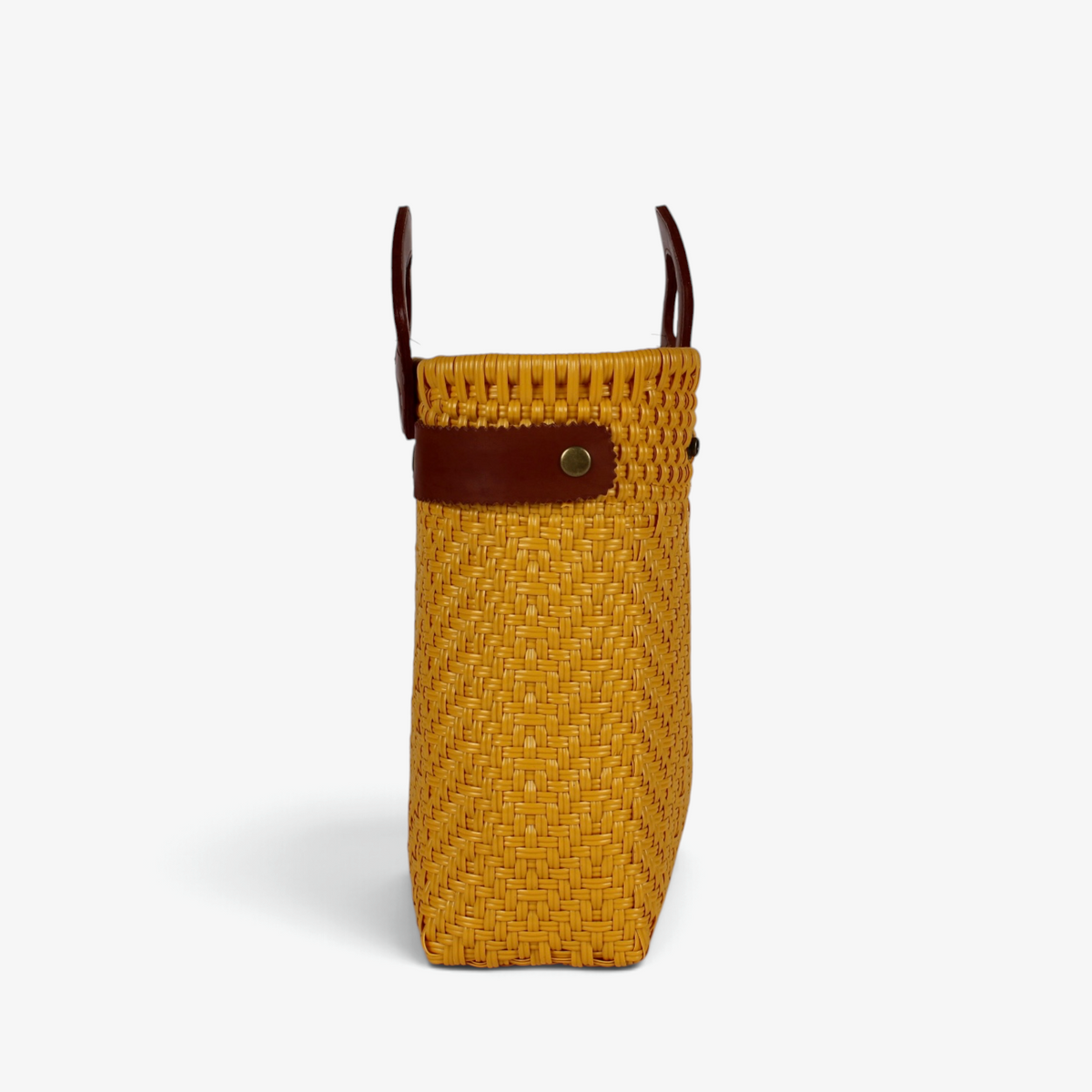 Side view of the mustard yellow woven basket bag showing its adjustable leather side strap