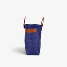 Side view of the royal blue woven tote showing its adjustable leather side strap