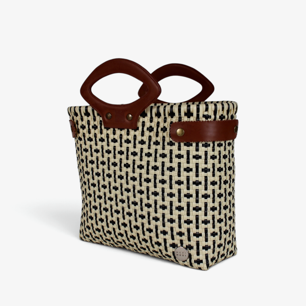Black and cream patterned basket bag with brown genuine leather handles, angled view