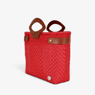 Bright red handwoven tote with brown genuine leather handles and snap side straps, angled view