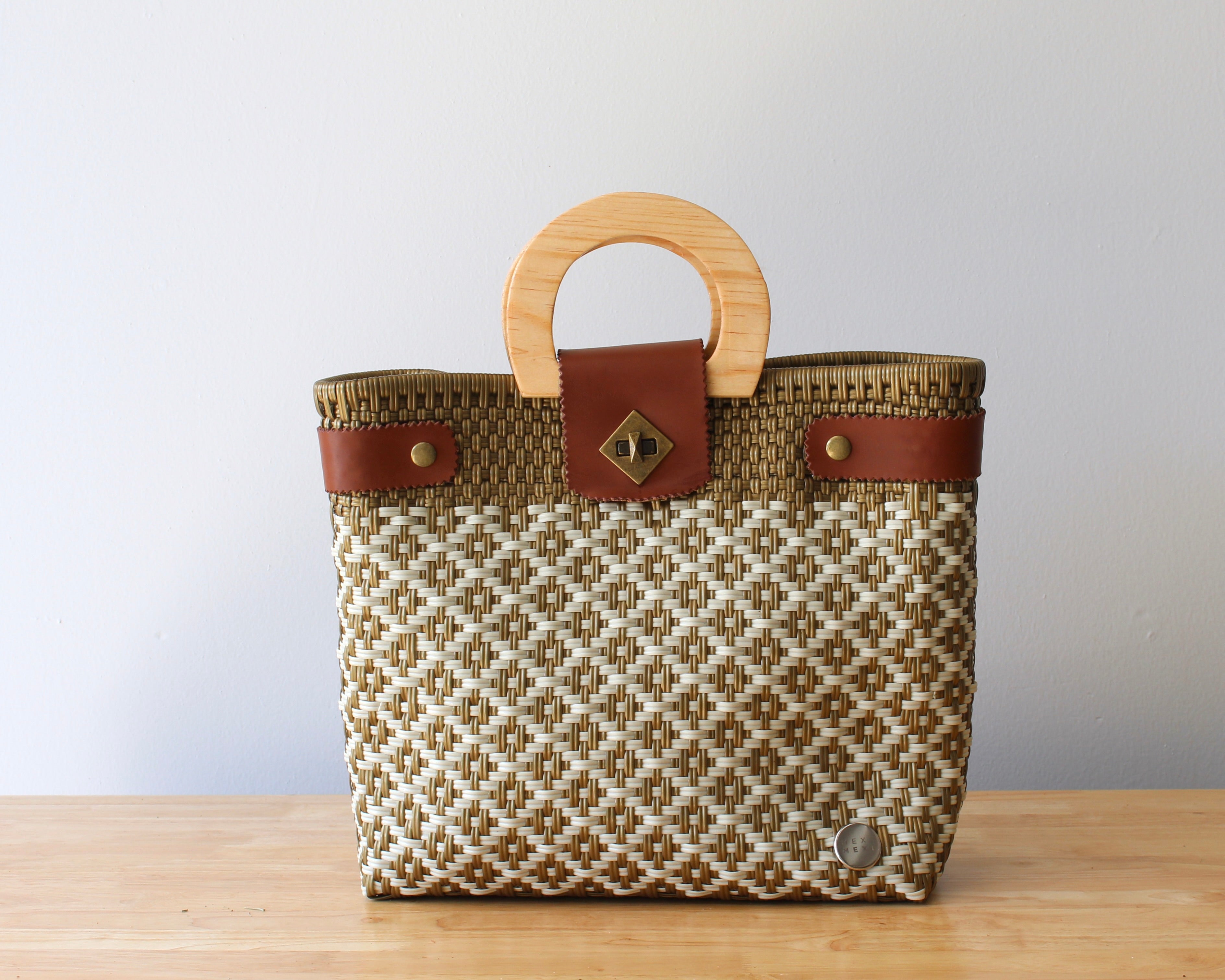 Beige and brown handwoven tote bag with leather handles on table