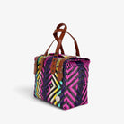 Pink and purple handwoven handbag with brown genuine leather handles and brass-tone hardware, angled view