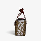 Side view of the pink, gold and white woven handbag with leather flap and snap closure