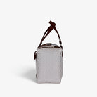 Side view of the white rainbow stripe woven handbag with leather flap and snap closure