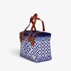 Navy and white handwoven handbag with brown genuine leather handles and brass-tone hardware, angled view