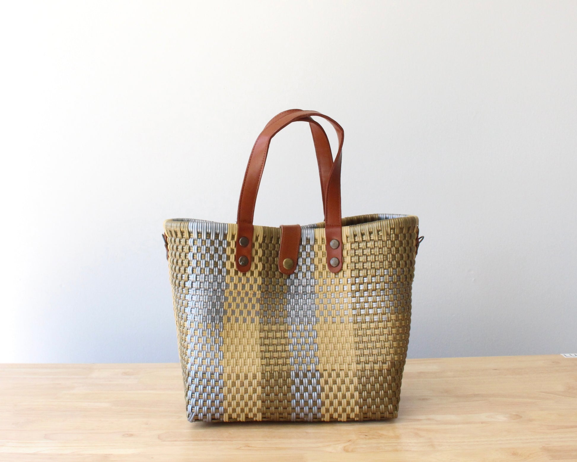 Close-up of the handwoven recycled plastic and soft leather handles, showing the texture and craftsmanship.