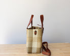 Close-up of the brown leather handles on a handmade recycled plastic purse, showcasing artisanal craftsmanship.