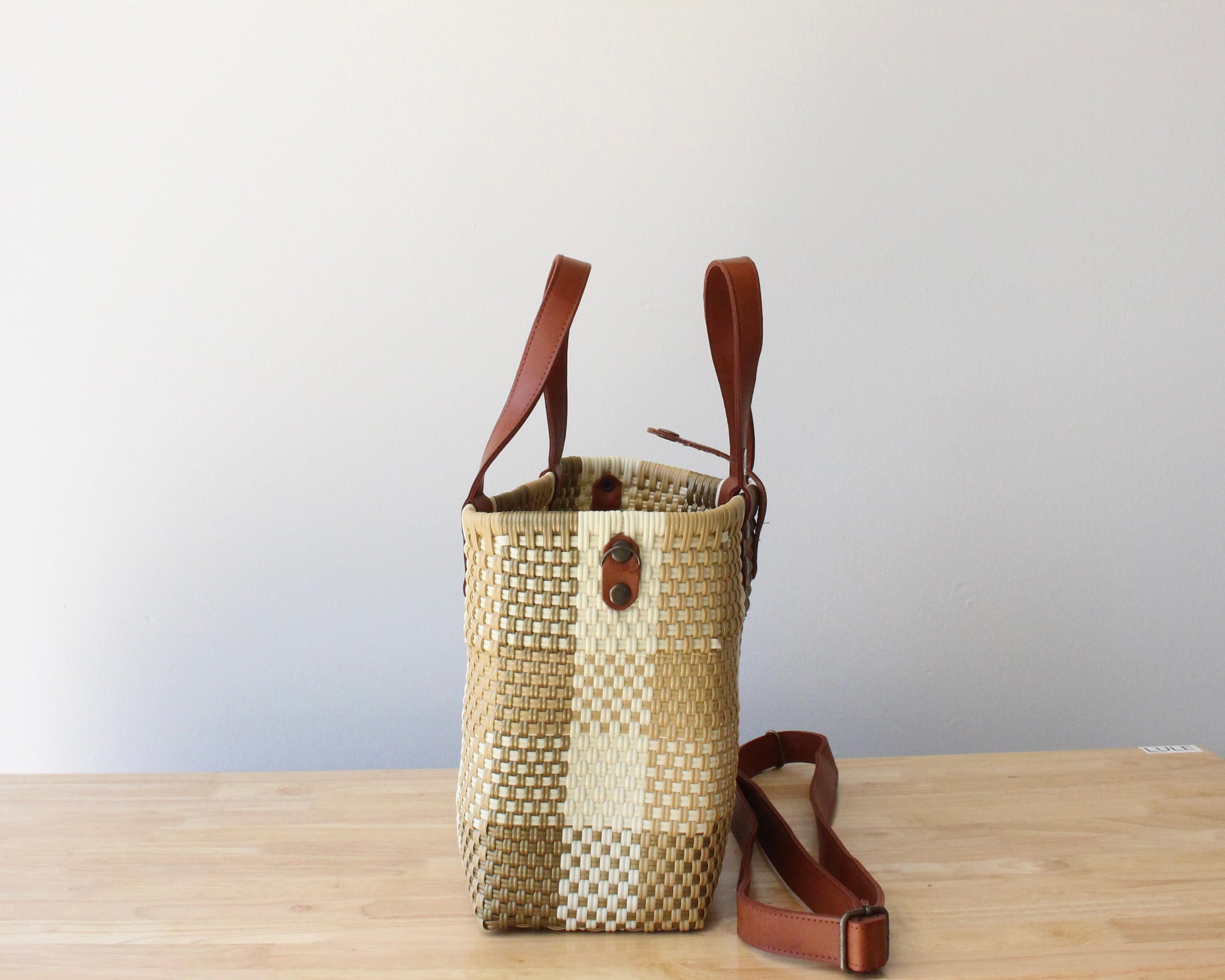 Close-up of the brown leather handles on a handmade recycled plastic purse, showcasing artisanal craftsmanship.