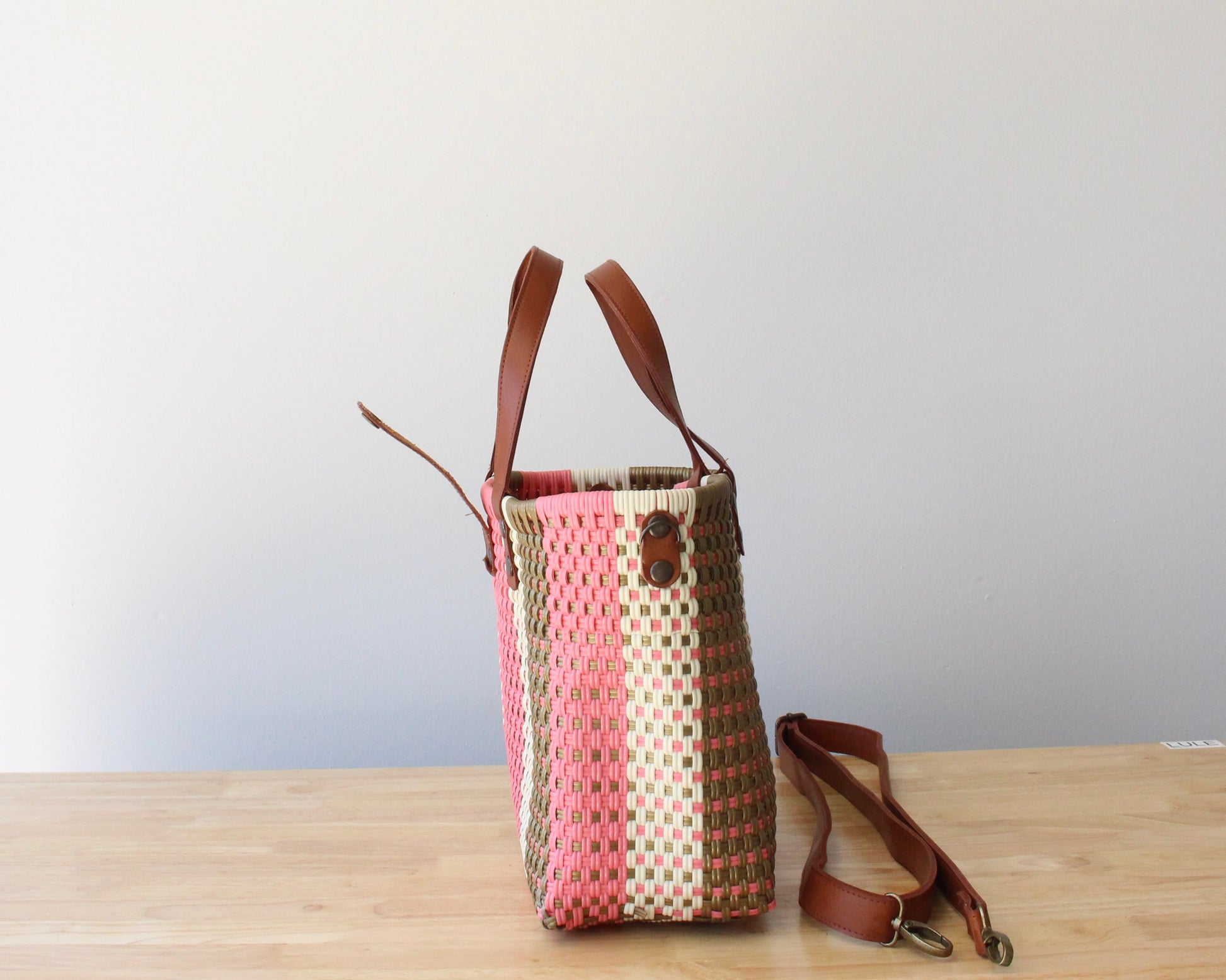 Close-up of the brown leather handles on a handmade recycled plastic purse, showcasing artisanal craftsmanship