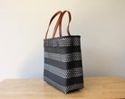Black and white handwoven Mexican tote bag with leather handles — angled view — Alma Rosa, Onyx — MexiMexi
