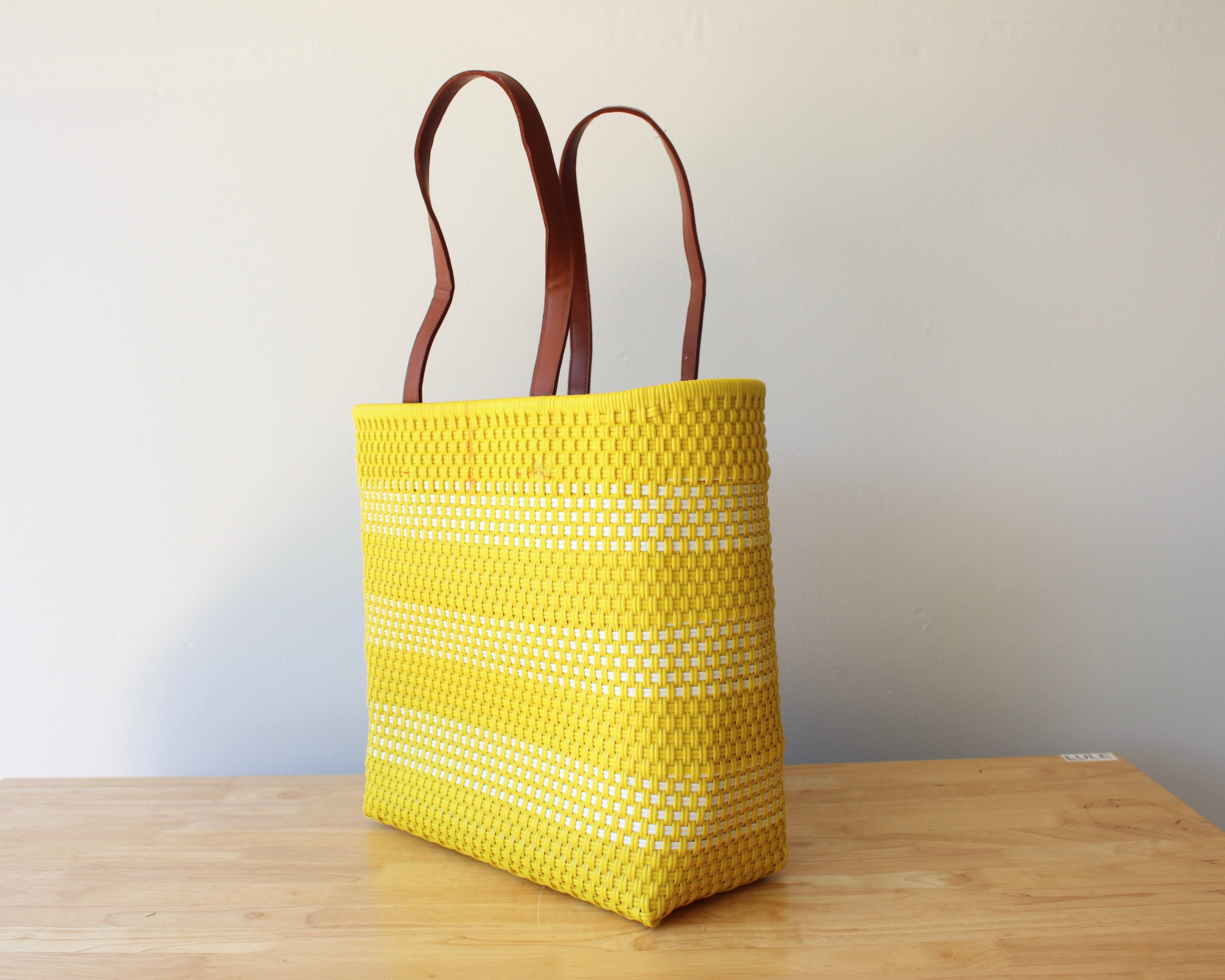 Yellow and white handwoven Mexican tote bag with leather handles — angled view — Alma Rosa, Sunshine — MexiMexi
